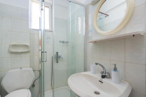 bagno con servizi igienici, lavandino e specchio di Annabel Apartments a Theologos