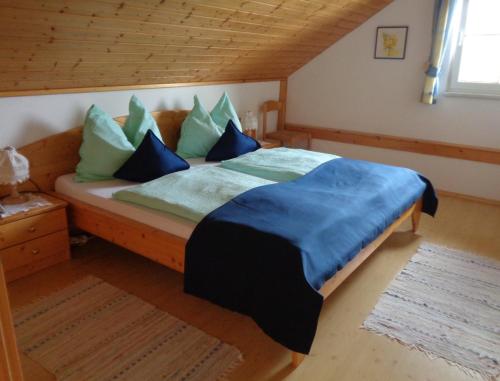 Stroblbauernhof في سيهام: غرفة نوم مع سرير ووسائد زرقاء وأخضر