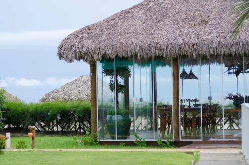 a hut with a grass roof and a table and chairs at Manati in Barra Grande