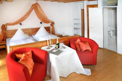 1 Schlafzimmer mit 2 roten Stühlen, einem Tisch und einem Bett in der Unterkunft Tagungshaus Kloster Heiligkreuztal in Altheim