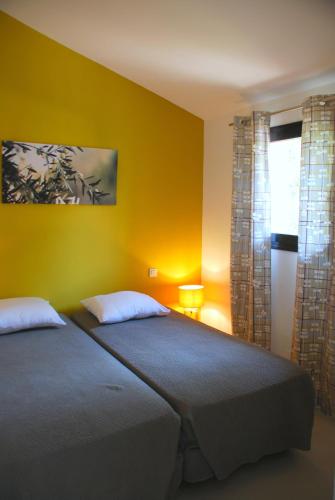 - une chambre avec un lit et un mur jaune dans l'établissement Mini Villa Santa, à Porto-Vecchio