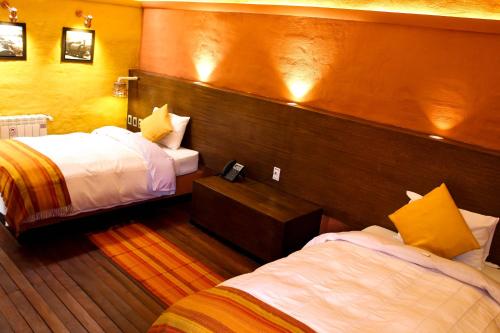 a hotel room with two beds and a wooden wall at Hotel Jardines de Uyuni in Uyuni