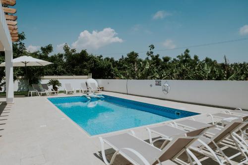 a swimming pool with white chairs and a swimming poolvisor at Villa Despoina in Paphos