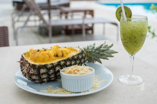 a pineapple on a plate next to a drink at Manati in Barra Grande