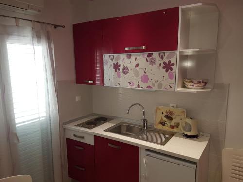 a small kitchen with red cabinets and a sink at House Villa Roza in Tučepi