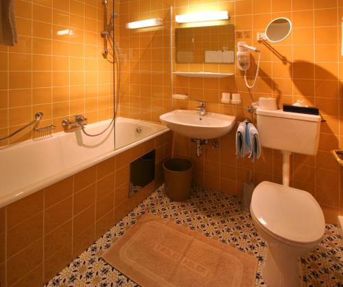 a bathroom with a toilet and a sink and a tub at Hotel Tiroler Adler - bed and breakfast in Waidring