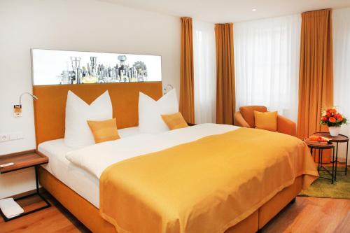 a hotel room with a large bed with a yellow blanket at Hotel Am Schloss *** Superior in Tübingen