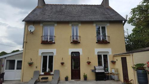 a yellow house with chairs in front of it at La Maison Celtique in Saint-Nicolas-du-Pélem