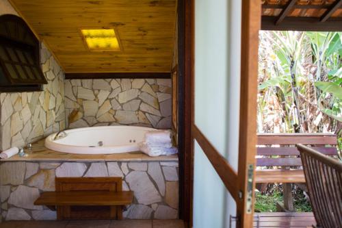 a bath tub in a bathroom with a stone wall at Pousada Montserrat in Visconde De Maua