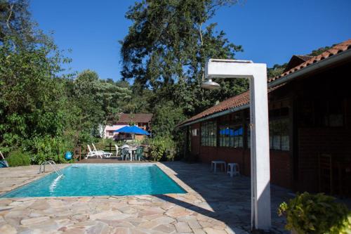 a swimming pool with a light next to a house at Pousada Montserrat in Visconde De Maua