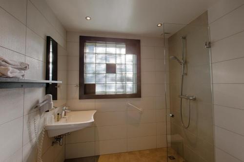 a bathroom with a sink and a shower at Hotel Restaurant des Vosges in Birkenwald