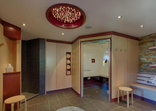 a room with a bathroom with a shower and chairs at Hotel Restaurant des Vosges in Birkenwald