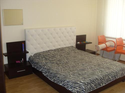スヴェティ・ヴラスにあるNick's Apartment in Sviati Vlasのベッドルーム1室(白いヘッドボードとオレンジの椅子が備わるベッド1台付)
