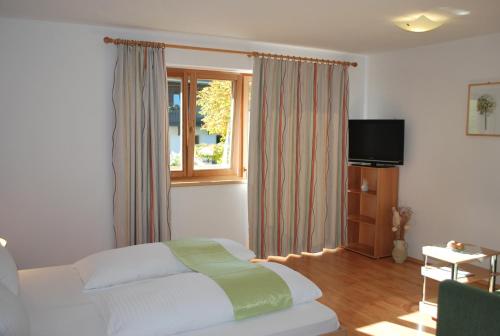 a bedroom with a bed and a television and a window at Berggasthof Bärnstatt in Scheffau am Wilden Kaiser
