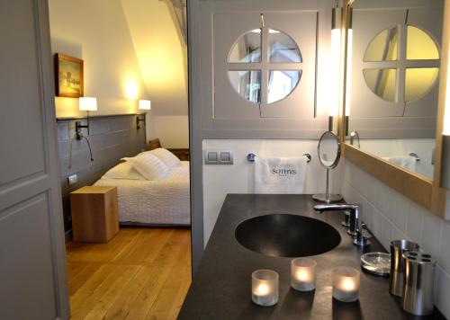 łazienka z umywalką oraz sypialnia z łóżkiem w obiekcie La Maison Des Jardins w mieście Auriac