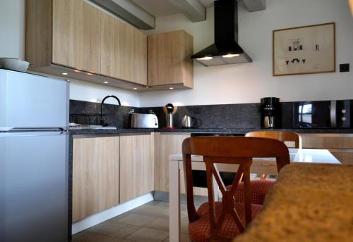 une cuisine avec des armoires en bois et un réfrigérateur blanc dans l'établissement La Maison Des Jardins, à Auriac