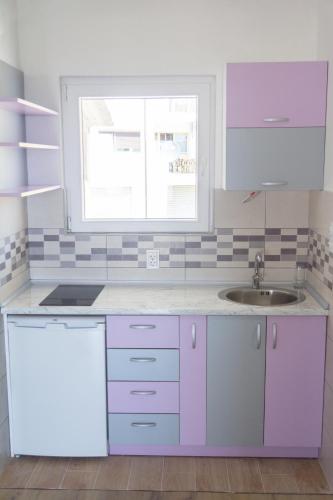 a kitchen with purple and white cabinets and a sink at Apartments Miki in Bar