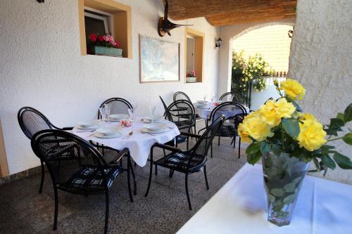 a table with chairs and a vase with yellow flowers at Restaurant penzion u Buchlovskeho zamku in Buchlovice