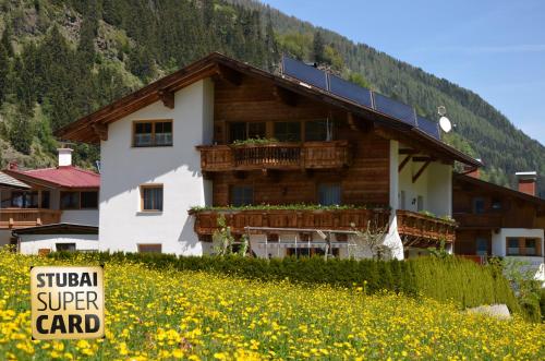 a building with a solar roof in a field of flowers at Haus Wally in Neustift im Stubaital