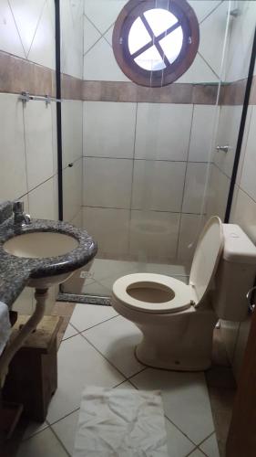 a bathroom with a toilet and a sink and a window at Pousada Pé na Areia in Garopaba