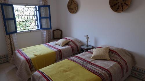 2 Betten in einem Zimmer mit Fenster in der Unterkunft Dar Chebba in Oualidia