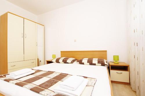 a white bedroom with a large bed with two pillows at Villa Vrbat in Seget Vranjica
