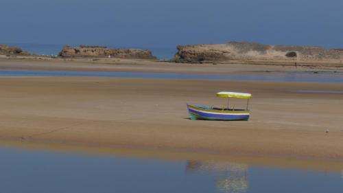 a boat sitting on the sand on the beach at Dar Chebba in Oualidia