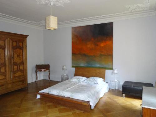 ストラスブールにあるLes Serruriers - Appartement Spacieux avec Terrasse & Parkingのベッドルーム1室(ベッド1台付)が備わります。壁には絵画が飾られています。