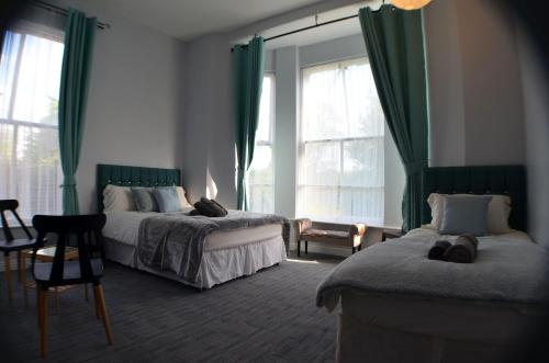 a bedroom with two beds with green curtains at Queens Guesthouse Manchester in Manchester
