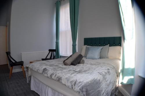 a bedroom with a large bed with a green headboard at Queens Guesthouse Manchester in Manchester