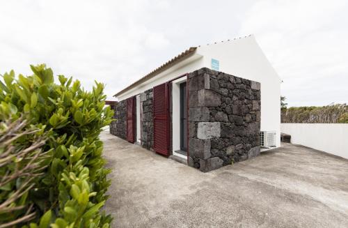 a house with a stone wall and red doors at Casa Da Poca Branca in Prainha de Baixo