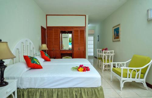 a bedroom with two beds and chairs with flowers on it at Dover Beach Hotel in Christ Church