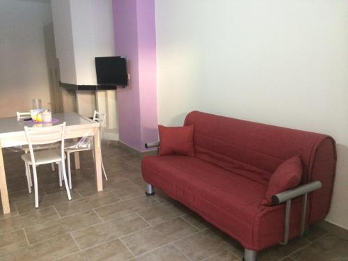 モルチャーノ・ディ・レウカにあるMonolocale del Salentoのリビングルーム(赤いソファ、テーブル付)