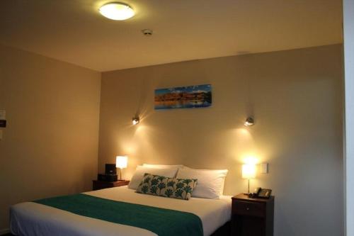 a bedroom with a bed and two lights on the wall at 540 on Great South Motel in Auckland