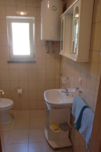 ein Badezimmer mit Waschbecken, Toilette und Fenster in der Unterkunft Apartment Andjel in Poreč
