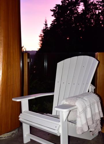 a white rocking chair sitting on a porch at The Rockwell-Harrison Guest Lodge in Harrison Hot Springs