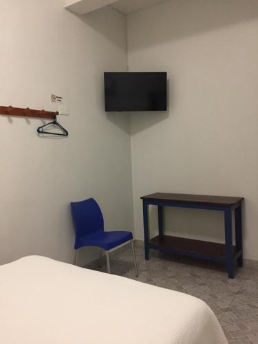 a room with a table and a blue chair and a tv at Hotel Florida in Villahermosa
