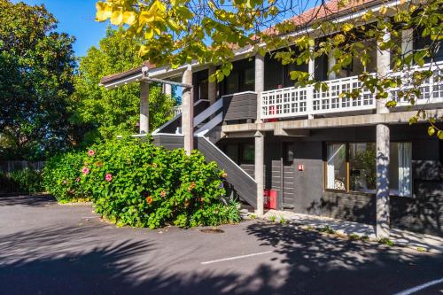 a house with a porch and flowers in front of it at Emerald Inn on Takapuna Beach in Auckland