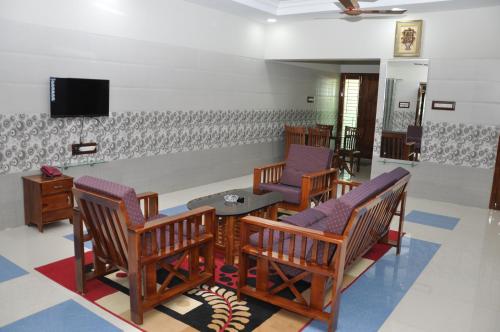 a waiting room with chairs and a tv on a wall at Hotel Green Palace in Thanjāvūr