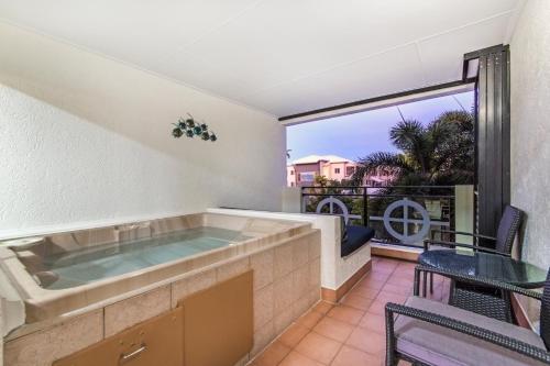 a hot tub on a balcony with a table and chairs at Regal Port Douglas in Port Douglas