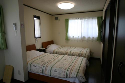 Una pequeña habitación con dos camas y una ventana. en Villa May Queen, en Fujikawaguchiko