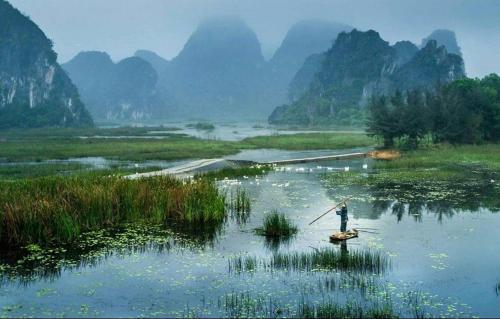 a person is rowing a boat in a river at Van Long Family Homestay in Ninh Binh
