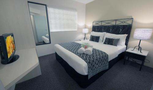 - une chambre avec un grand lit et une télévision dans l'établissement Inn Cairns, à Cairns