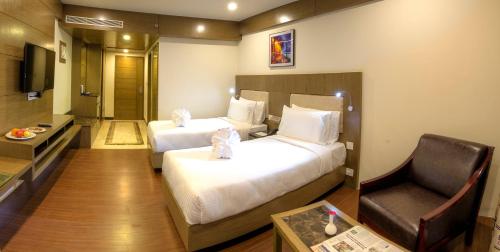 a hotel room with two beds and a chair at Hotel Benzz Park Vellore in Vellore