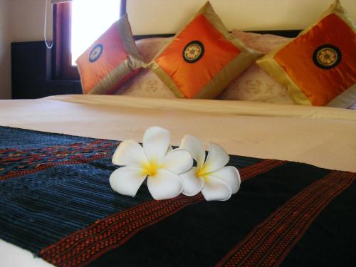 two white flowers on a bed in a room at Baan Banyan Villa, wood house short walk to Mae Nam beach in Mae Nam