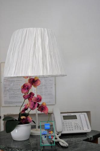 a lamp on a desk with a phone and a flower at Hotel Cecile in Pisa