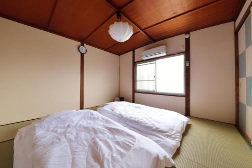 a bedroom with a bed with white sheets and a window at Eisukeya in Gion in Kyoto