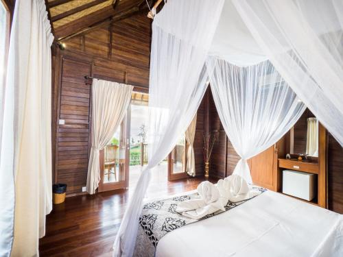 Schlafzimmer mit einem Bett mit weißen Vorhängen in der Unterkunft Bali Belva in Nusa Lembongan