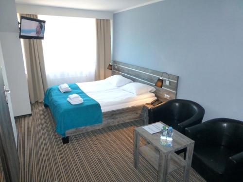 a hotel room with a bed and a chair at Hotel Giżycko in Giżycko