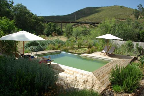 a swimming pool with two umbrellas and two lounge chairs at Quinta do Arade - casa 4 pétalas in Barranco do Resgalho